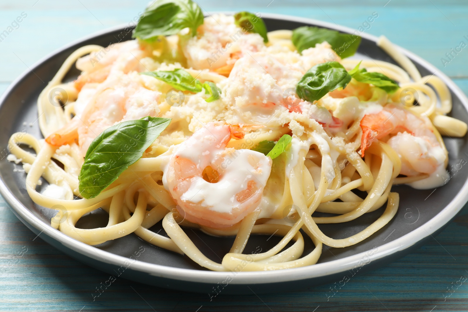 Photo of Tasty pasta with shrimps on light blue wooden table, closeup