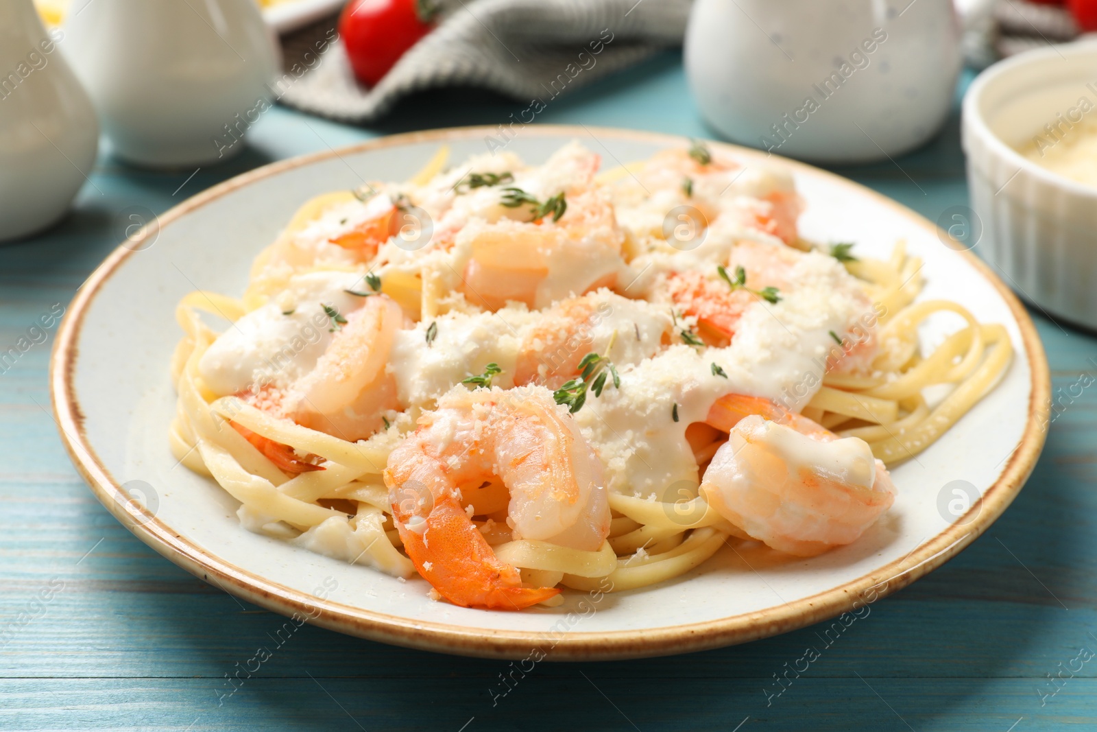 Photo of Tasty pasta with shrimps, creamy sauce and cheese on light blue wooden table, closeup