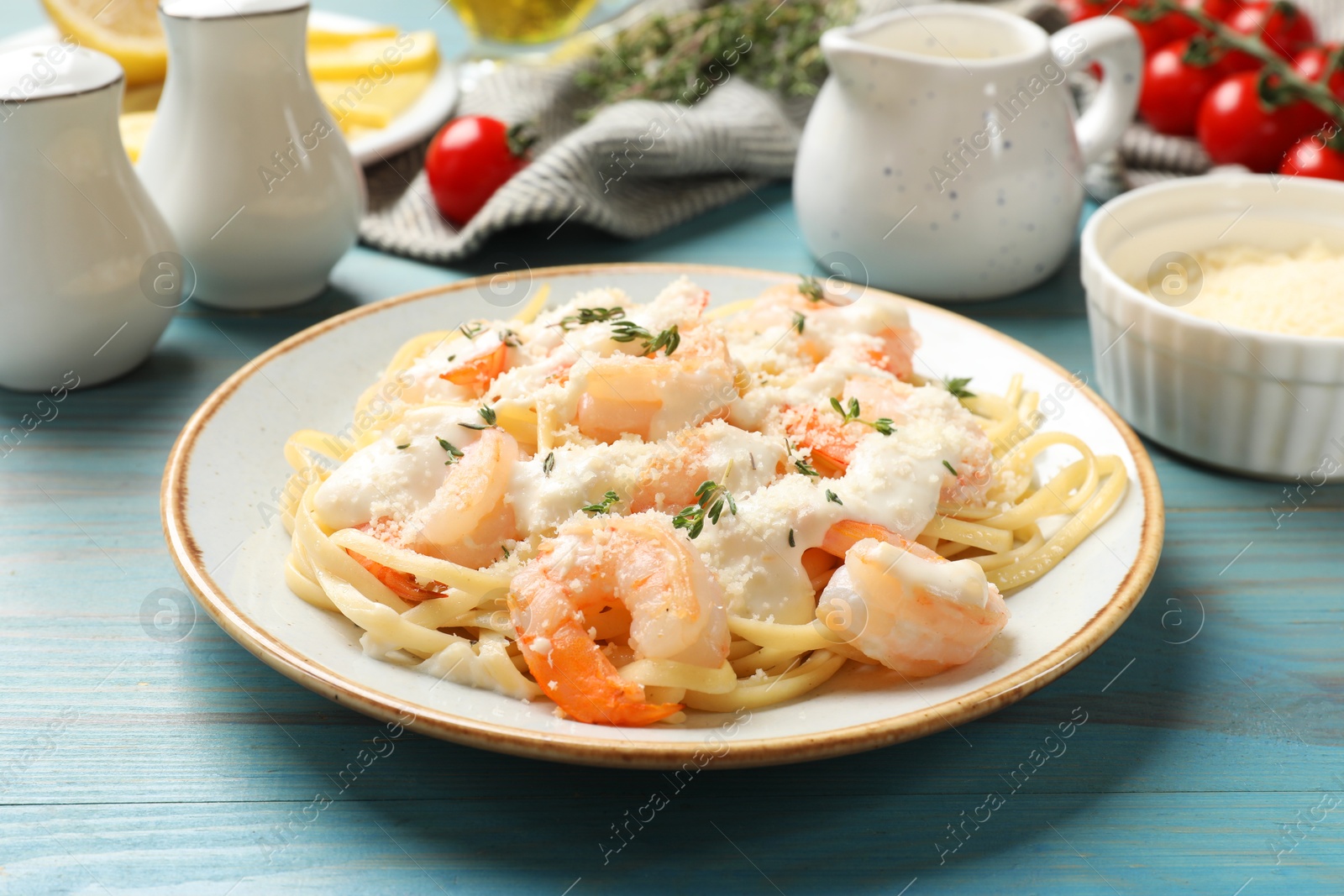 Photo of Tasty pasta with shrimps, creamy sauce and cheese on light blue wooden table, closeup