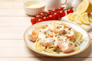 Photo of Tasty pasta with shrimps, creamy sauce and cheese served on light wooden table, closeup