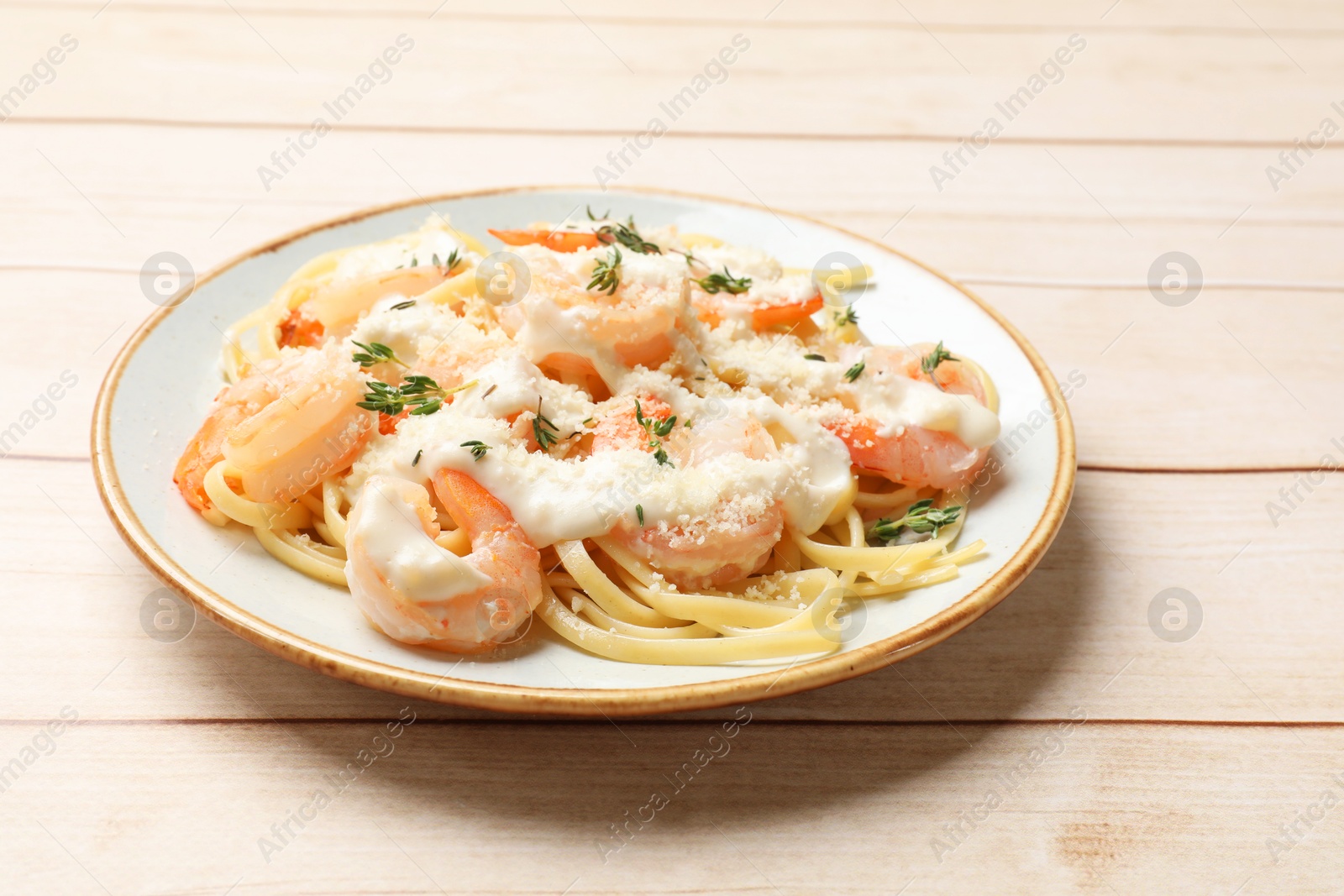 Photo of Tasty pasta with shrimps, creamy sauce and cheese on light wooden table, closeup