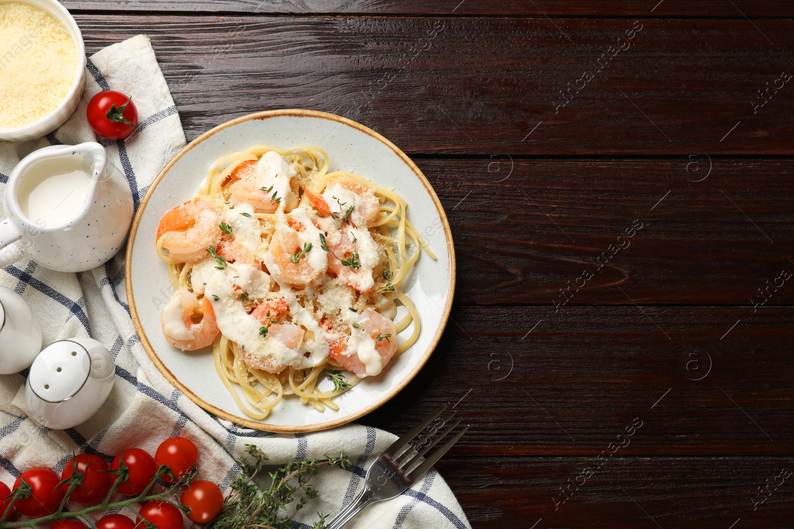 Photo of Tasty pasta with shrimps, creamy sauce and cheese on wooden table, flat lay. Space for text