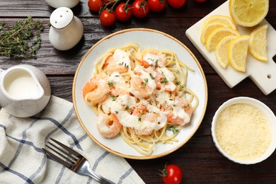 Photo of Tasty pasta with shrimps, creamy sauce and cheese on wooden table, flat lay