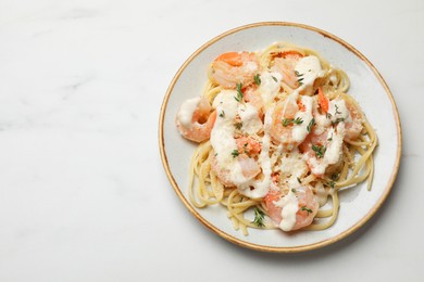 Photo of Tasty pasta with shrimps, creamy sauce and cheese on white marble table, top view. Space for text