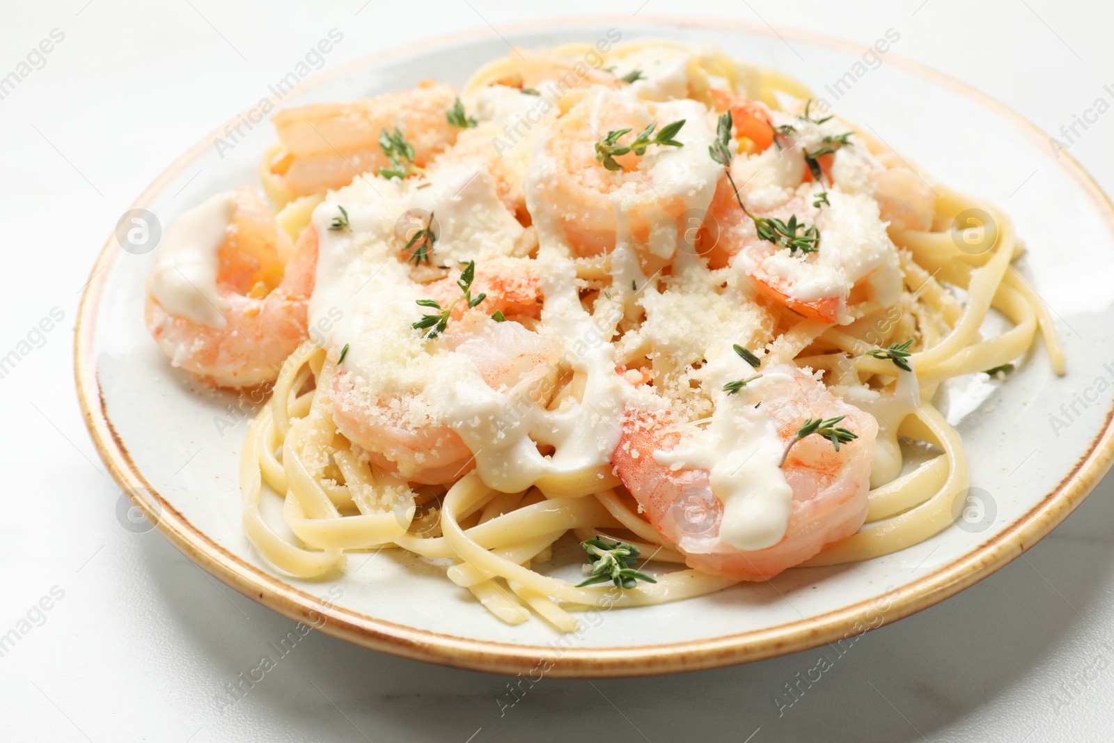 Photo of Tasty pasta with shrimps, creamy sauce and cheese on white table, closeup