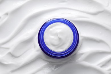 Face cream in jar on cosmetic product, top view