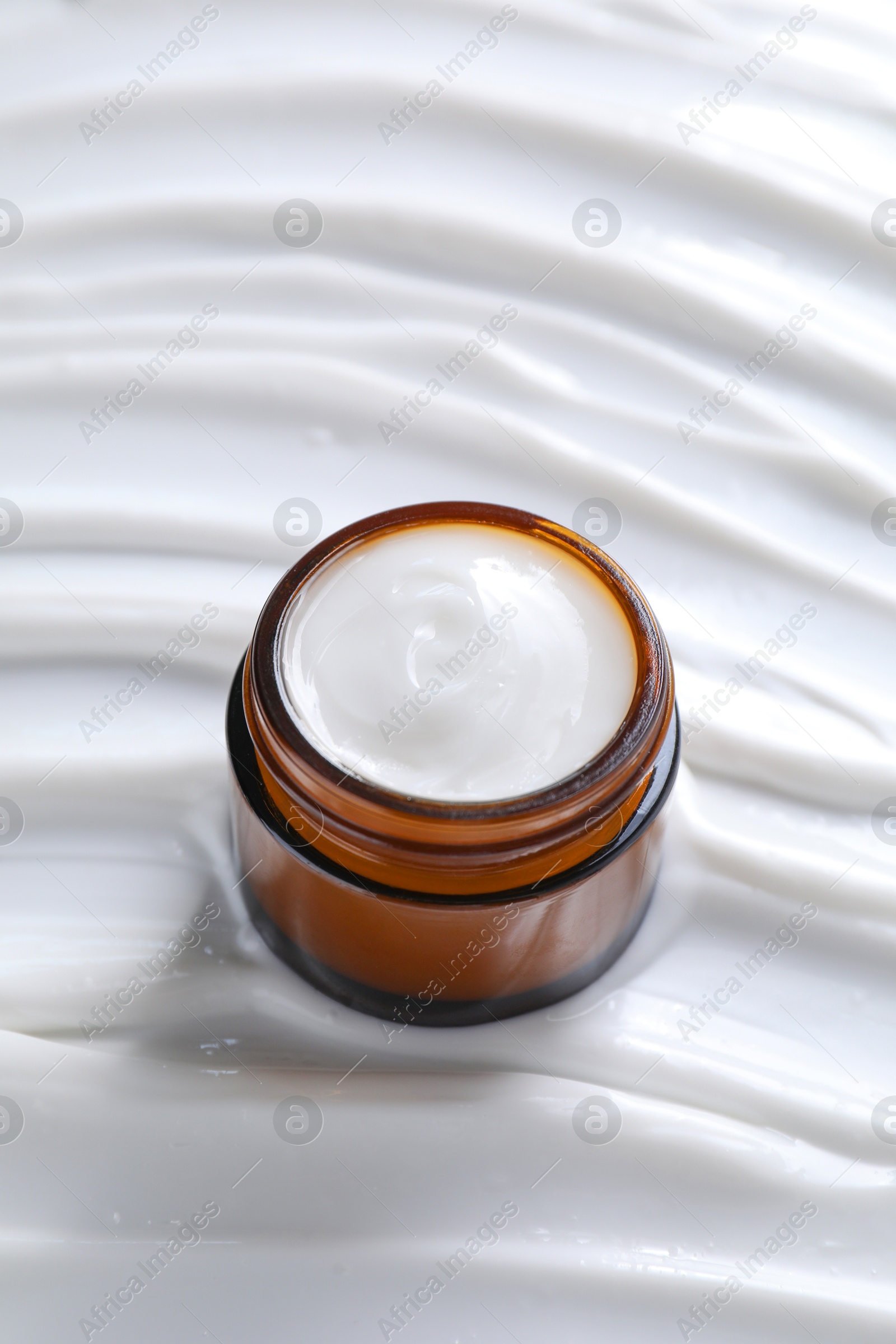 Photo of Face cream in jar on cosmetic product, closeup