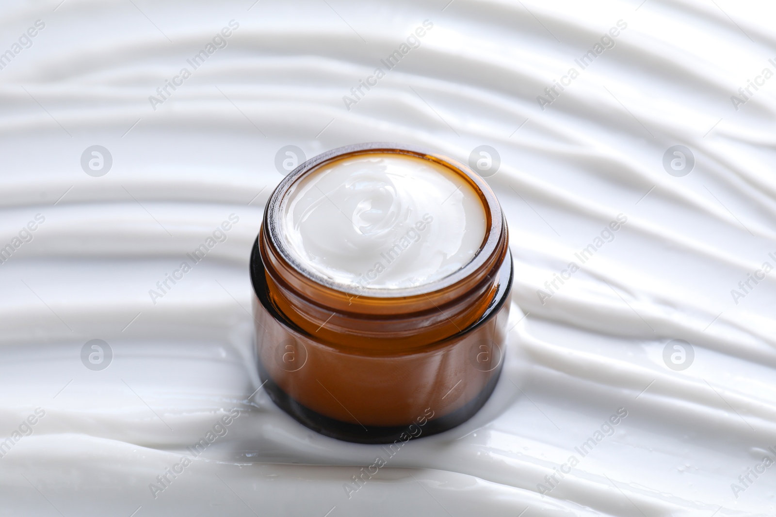 Photo of Face cream in jar on cosmetic product, closeup