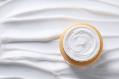 Face cream in jar on cosmetic product, top view. Space for text