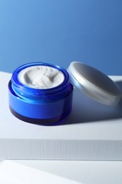 Photo of Stylish presentation of face cream in jar against light blue background