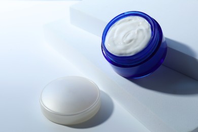 Face cream in jar and lid on white background. Cosmetic product