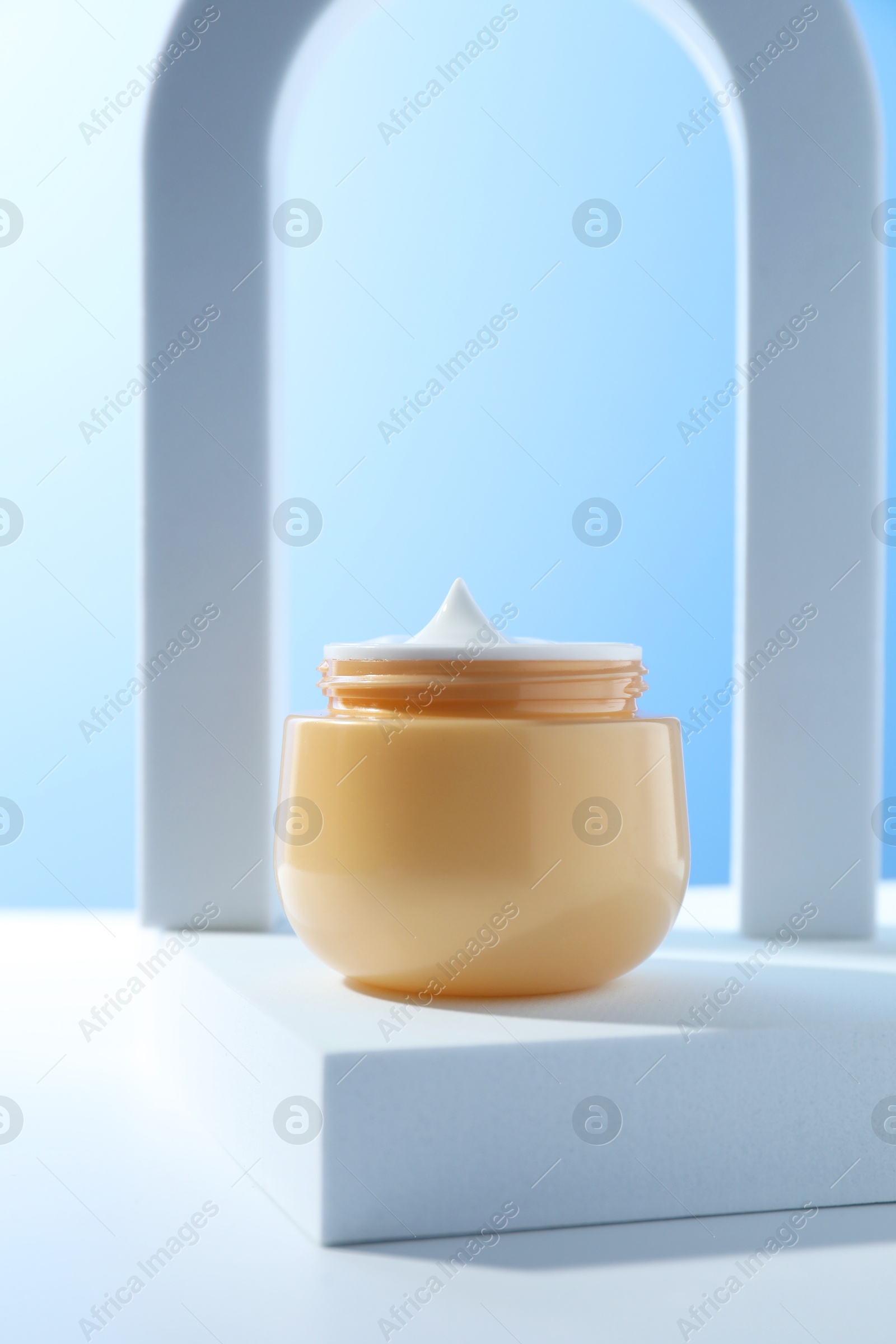 Photo of Stylish presentation of face cream in jar against light blue background