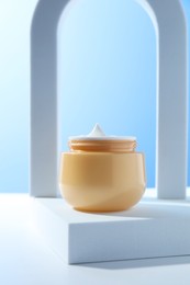 Stylish presentation of face cream in jar against light blue background