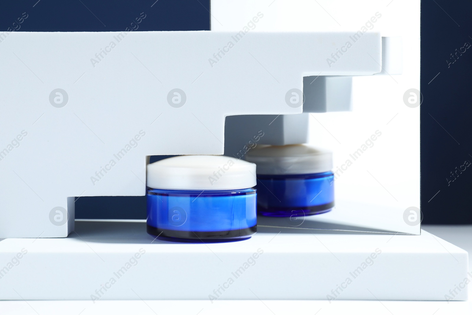 Photo of Stylish presentation of face cream against blue background