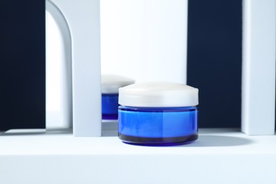 Photo of Stylish presentation of face cream against blue background