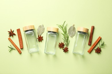 Photo of Different spices and glass jars on green background, flat lay