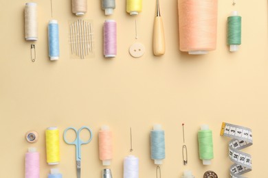 Photo of Flat lay composition with different sewing supplies on beige background. Space for text