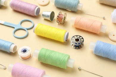 Photo of Different sewing supplies on beige background, closeup