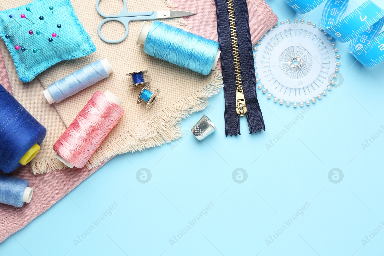 Photo of Flat lay composition with different sewing supplies on light blue background. Space for text