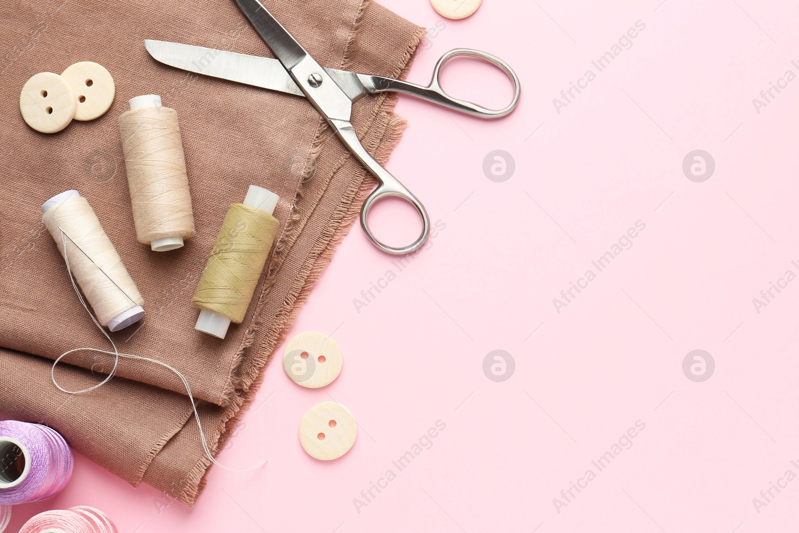 Photo of Flat lay composition with different sewing supplies on pink background. Space for text