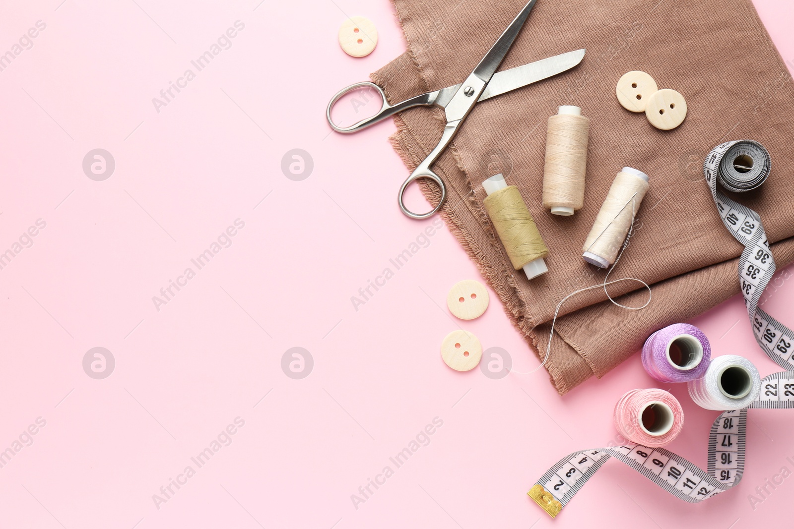 Photo of Flat lay composition with different sewing supplies on pink background. Space for text