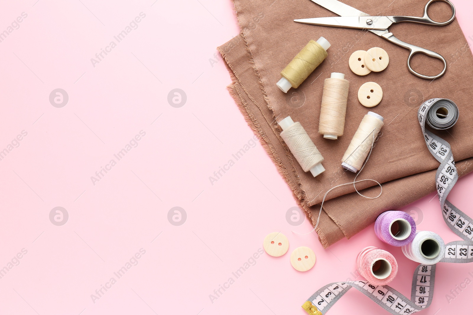 Photo of Flat lay composition with different sewing supplies on pink background. Space for text