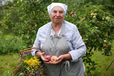 Senior woman with apples and wildflowers outdoors