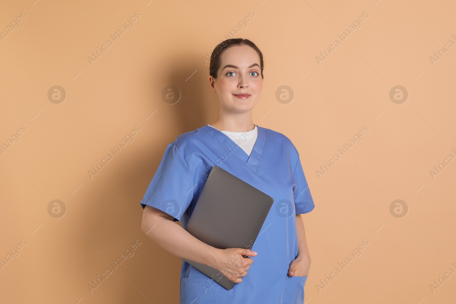 Photo of Portrait of nurse with laptop on dark beige background