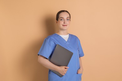 Photo of Portrait of nurse with laptop on dark beige background