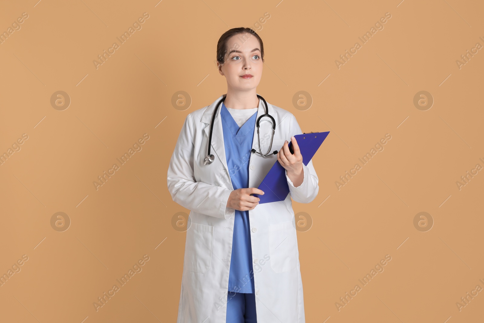 Photo of Portrait of professional nurse with clipboard on dark beige background