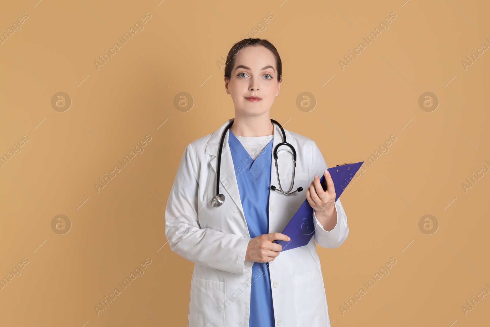 Photo of Portrait of professional nurse with clipboard on dark beige background