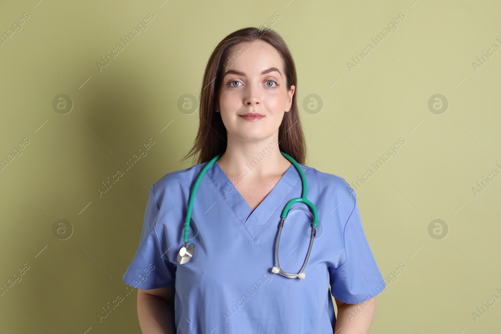 Photo of Professional nurse with stethoscope on pale green background