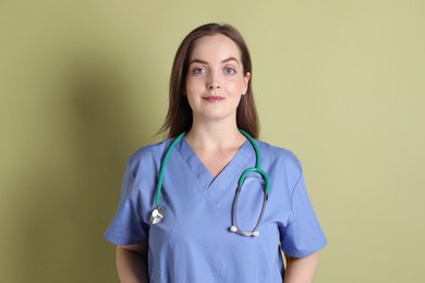 Photo of Professional nurse with stethoscope on pale green background