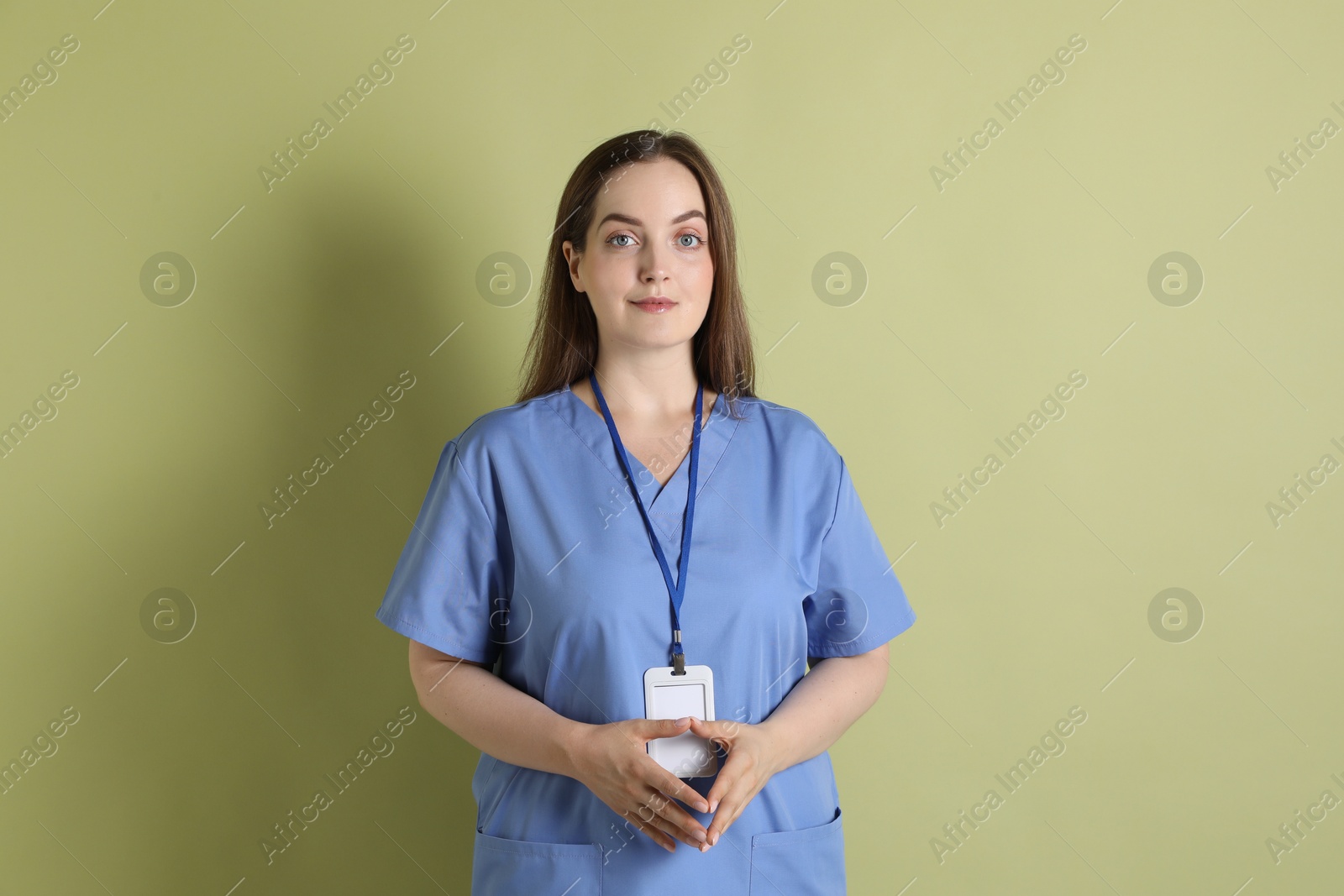 Photo of Professional nurse with badge on pale green background