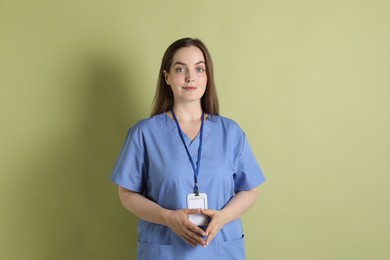 Photo of Professional nurse with badge on pale green background