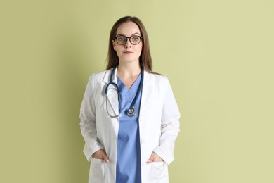 Portrait of professional nurse with stethoscope on pale green background