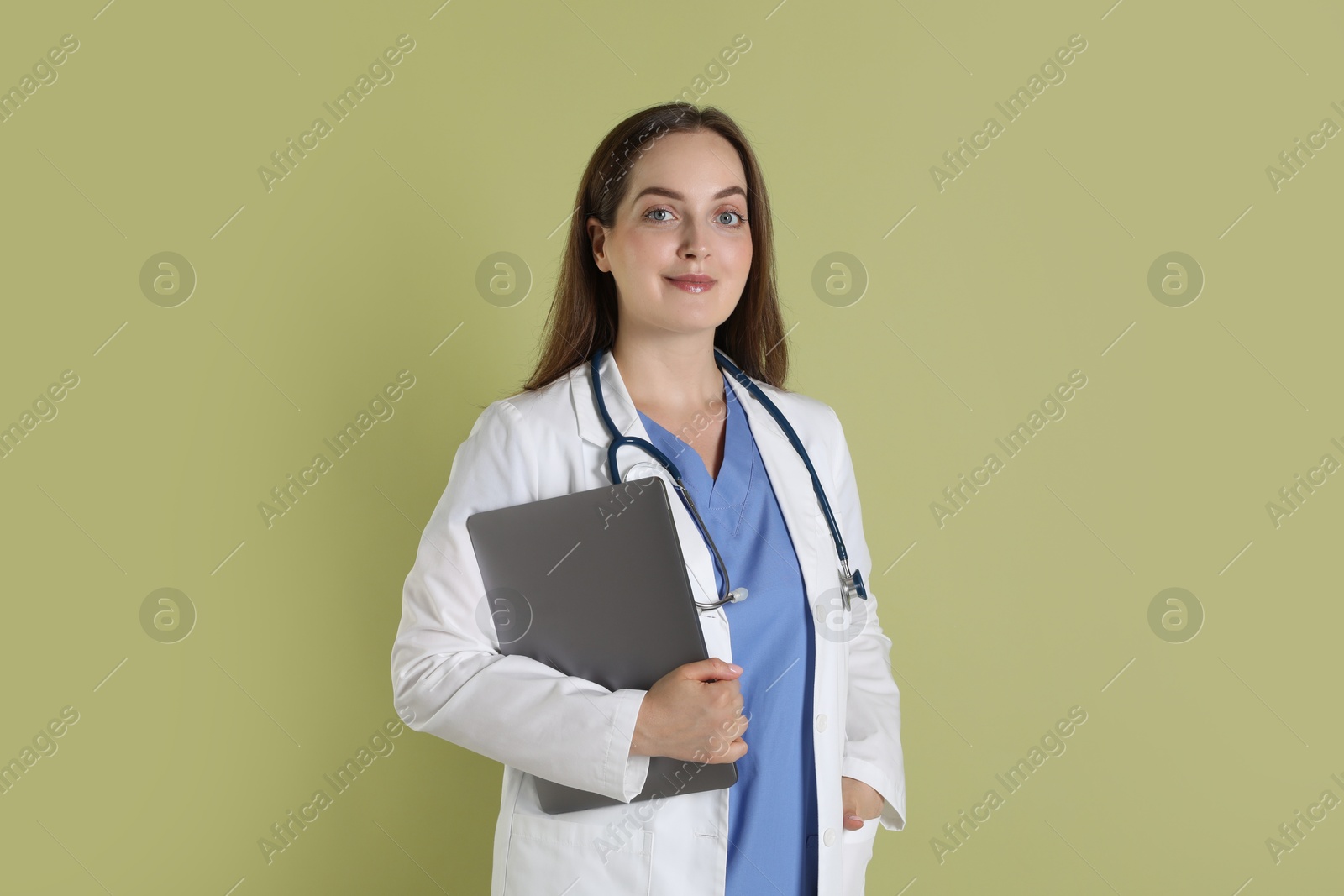 Photo of Professional nurse with laptop and stethoscope on pale green background