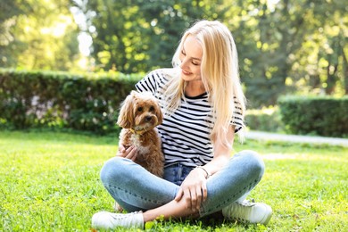 Photo of Beautiful young woman with cute dog on green grass in park