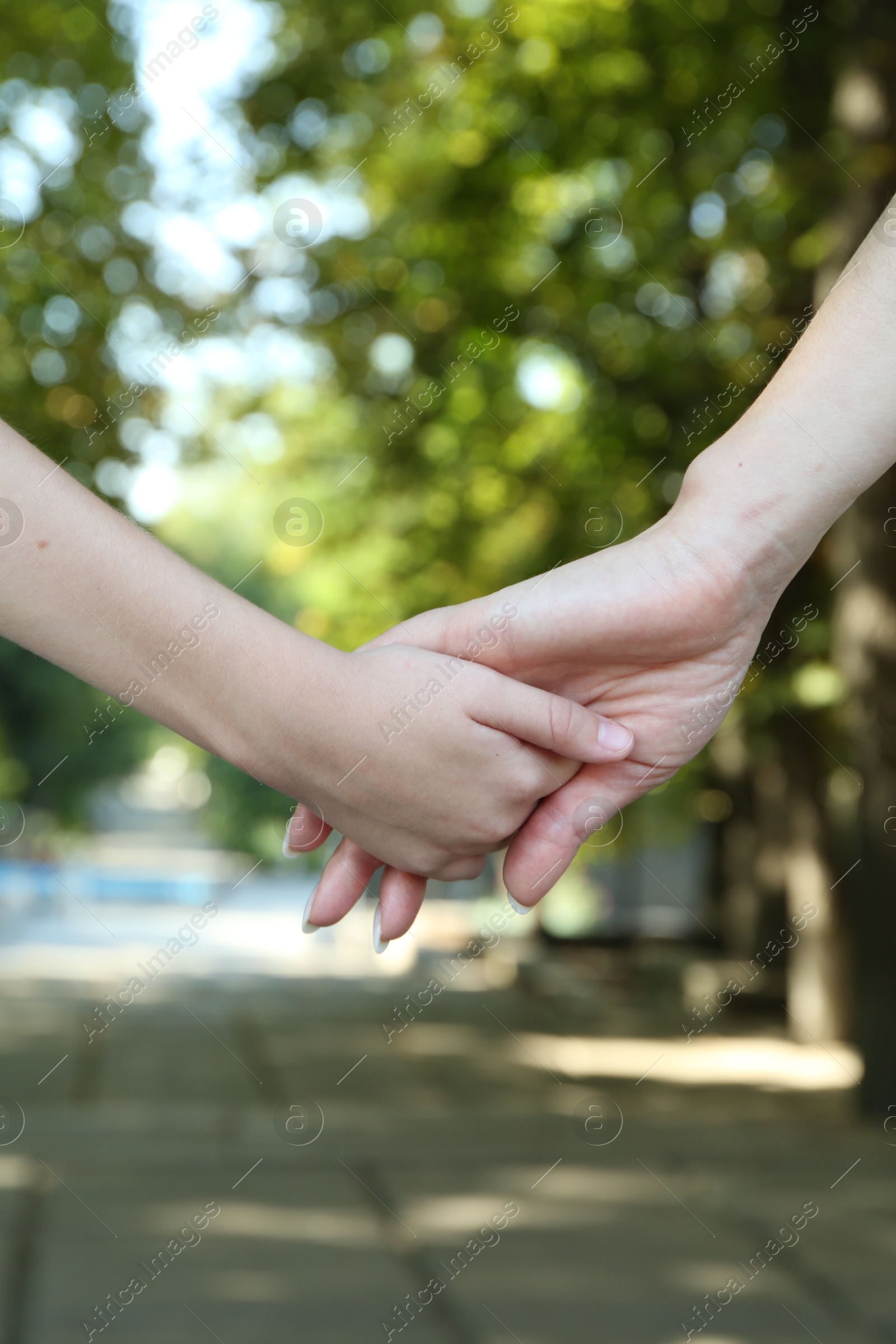 Photo of Mother and daughter holding hands in park, closeup