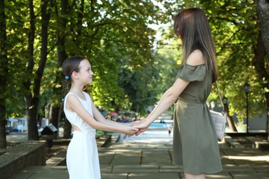 Mother and daughter holding hands in park