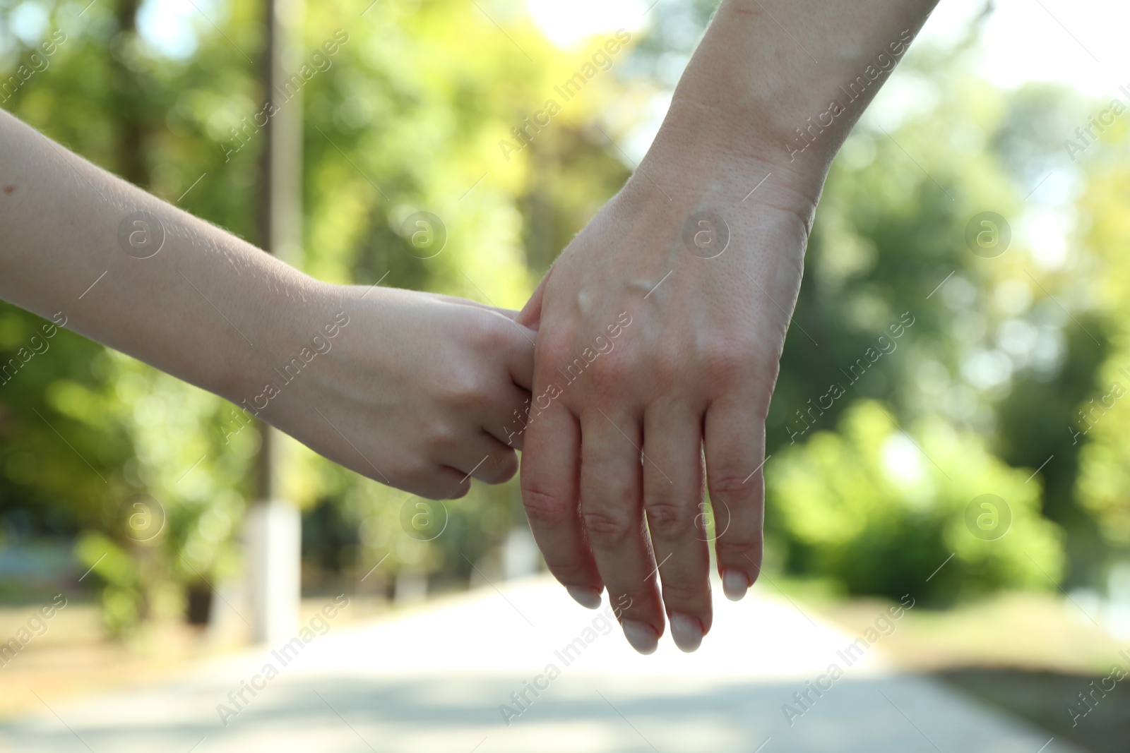 Photo of Mother and daughter holding hands in park, closeup