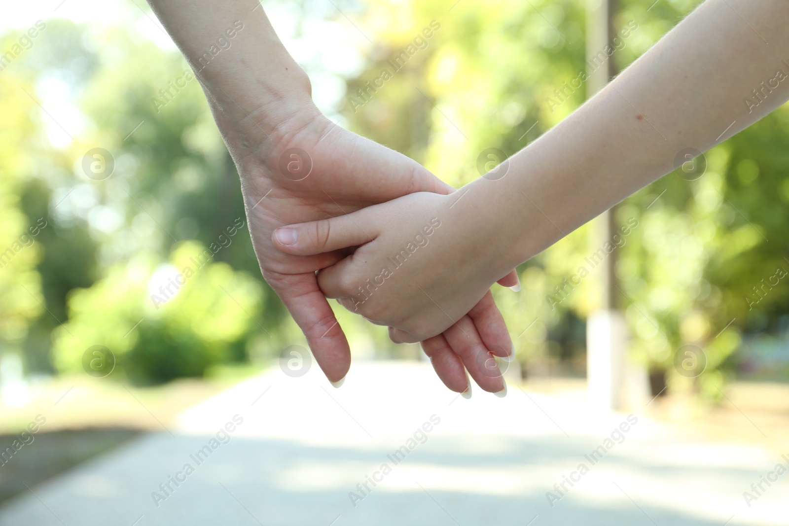 Photo of Mother and daughter holding hands in park, closeup