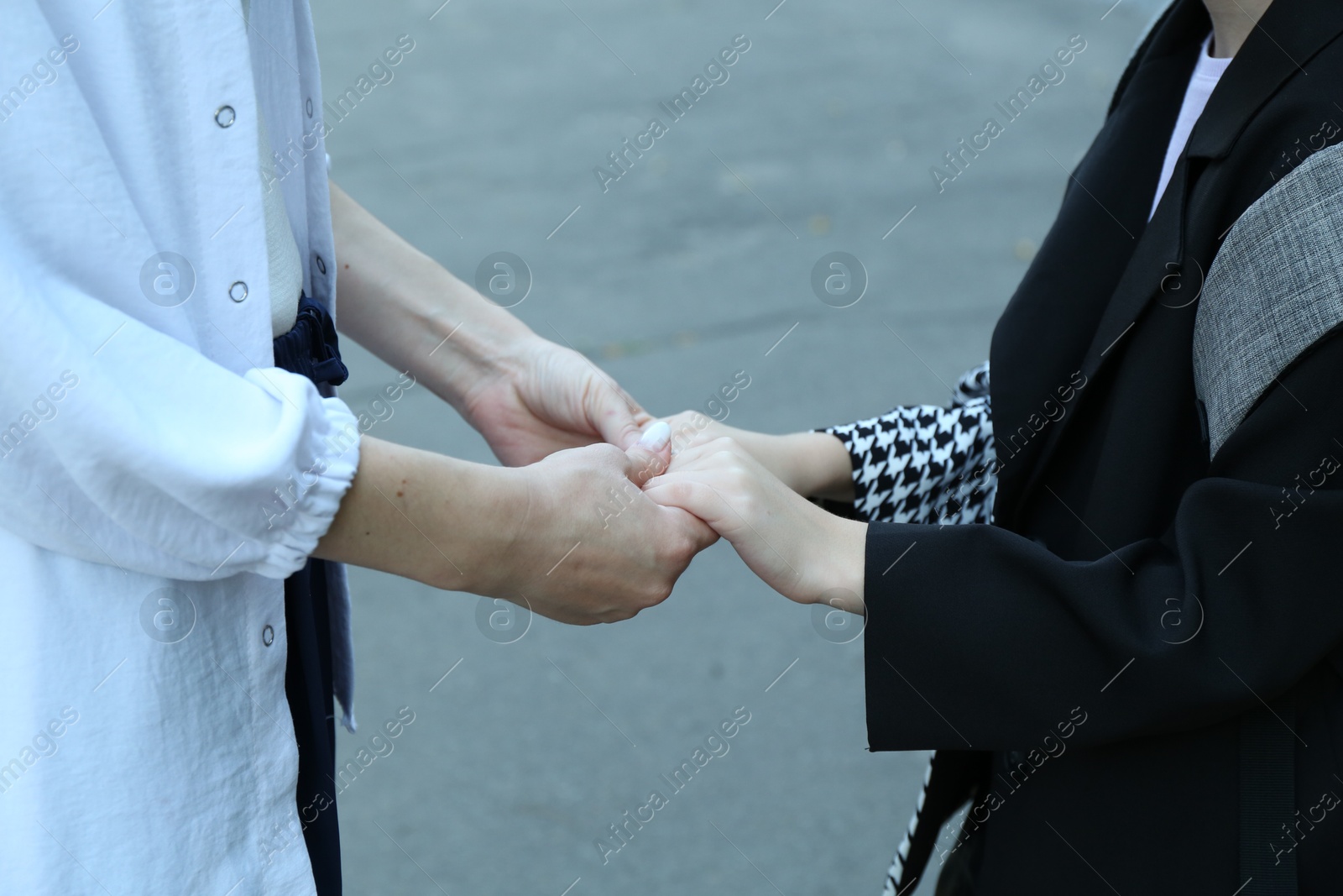 Photo of Mother and daughter holding hands outdoors, closeup