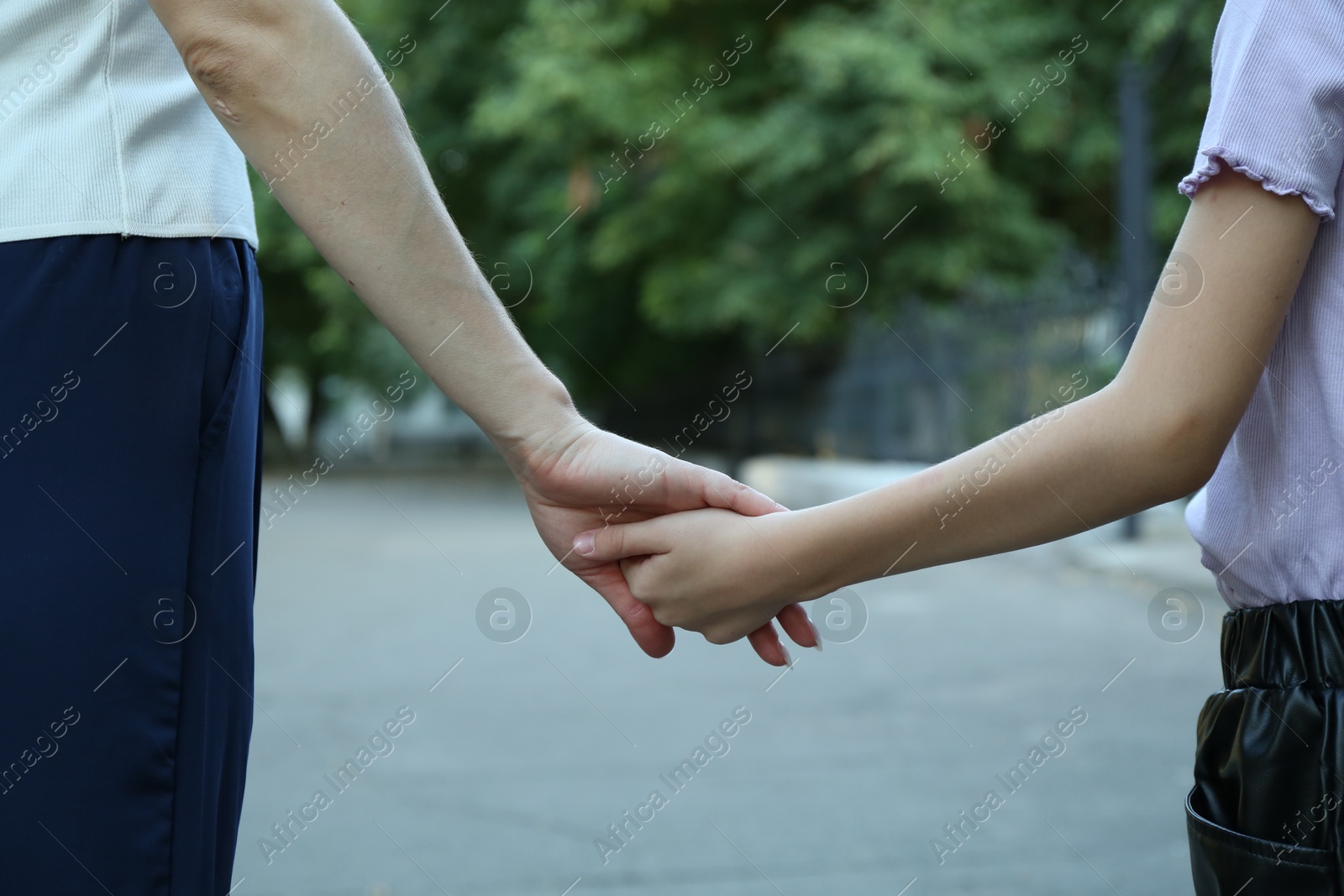 Photo of Mother and daughter holding hands outdoors, closeup