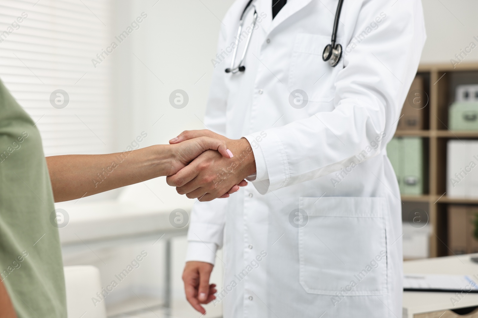 Photo of Doctor shaking hands with patient in hospital, closeup