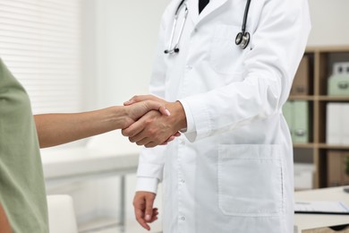 Doctor shaking hands with patient in hospital, closeup