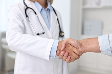 Photo of Doctor shaking hands with patient in hospital, closeup