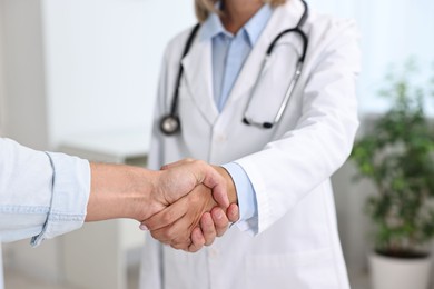 Doctor shaking hands with patient in hospital, closeup