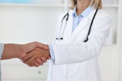 Doctor shaking hands with patient in hospital, closeup