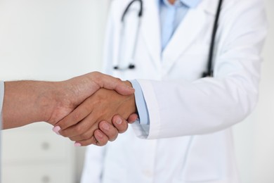 Doctor shaking hands with patient in hospital, closeup